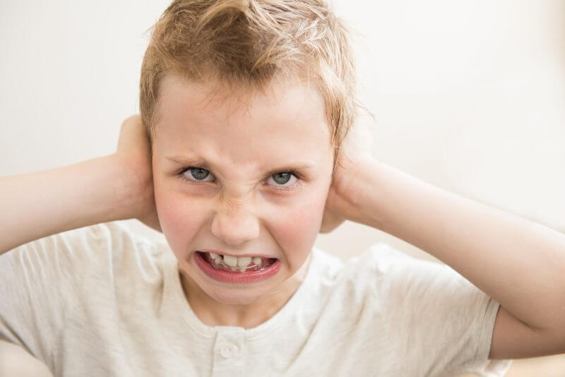 Does my child have sensory processing disorder? Boy with hands over ears.