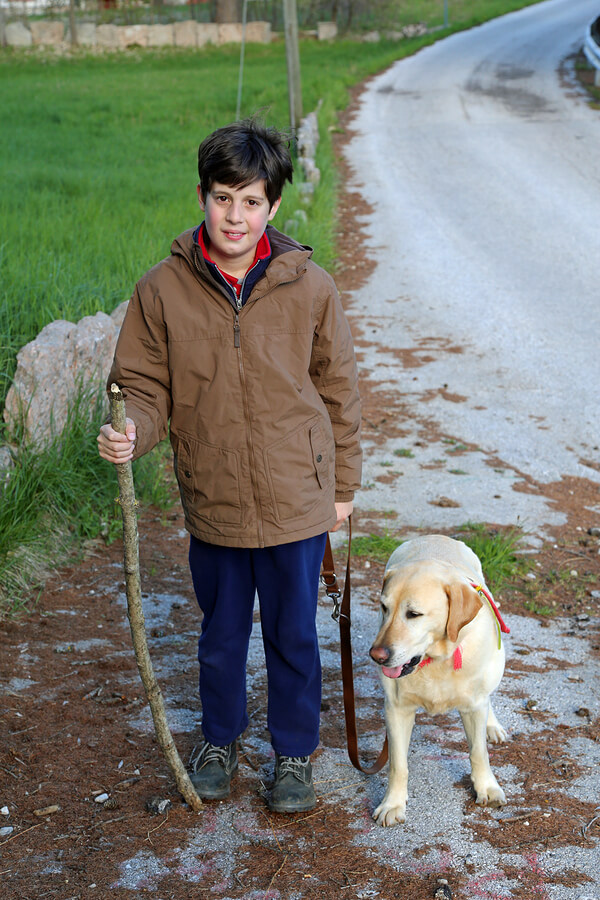 Measuring Quality of LIfe for those with ASD, starts with happiness. Boy walks a dog on a leash