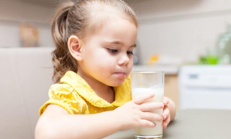 Gluten Free Dairy Free Diet for chiAutism. Child girl drinking milk at the kitchen