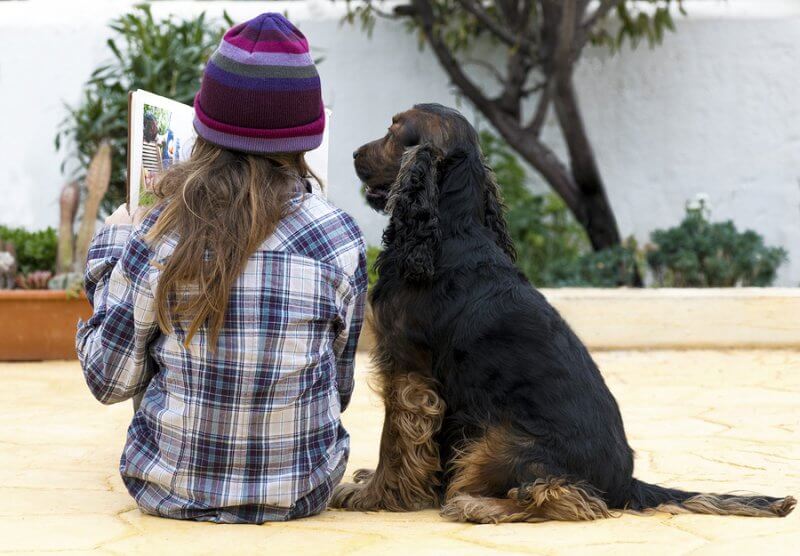 A child reading to a dog. Reading to animals can help children with autism