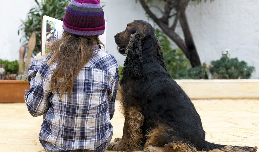 A child reading to a dog. Reading to animals can help children with autism