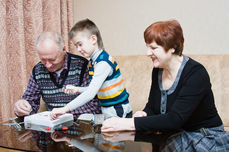 A grand mother and grand father play with their autistic grandchild
