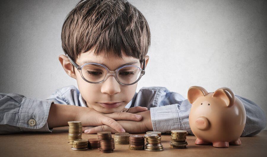 money managment for boy with autism looking at piles of money with his piggy bank