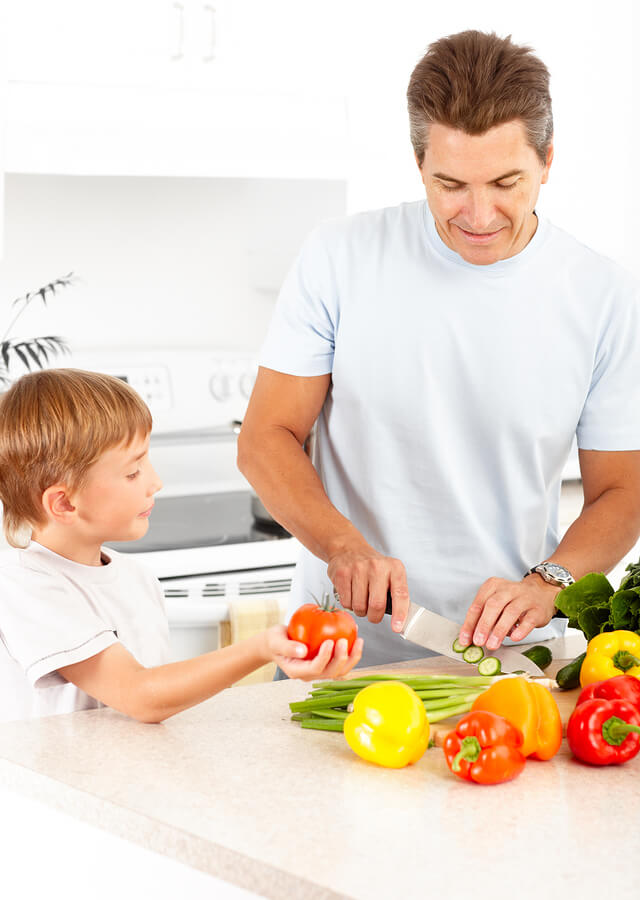 Happy family. Father and son cooking at kitchen teaching cooking to kids with autism