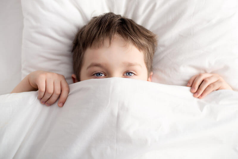 Little Boy In Bed Covering His Face With White Blanket Sleep disorders autism