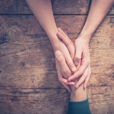 Keeping marriage strong with autism diagnosis: Close up on a man and a woman holding hands at a wooden table